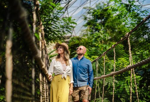 Couple walking across a wobbly bridge in the Rainforest Biome